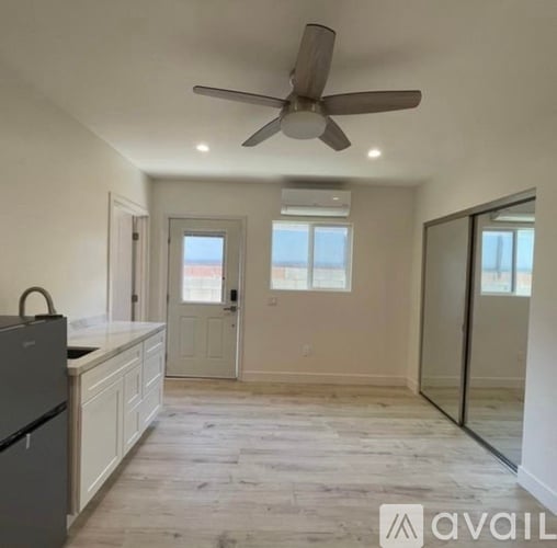 A spacious kitchen with a ceiling fan and a refrigerator.