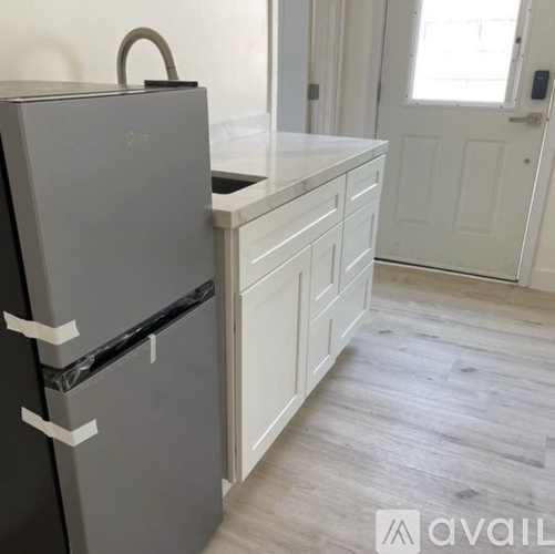 A grey fridge in a kitchen with white cabinets.