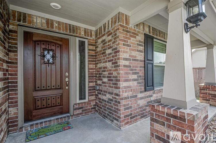 A brown door with a clock on it is on the left side of a brick pillar.