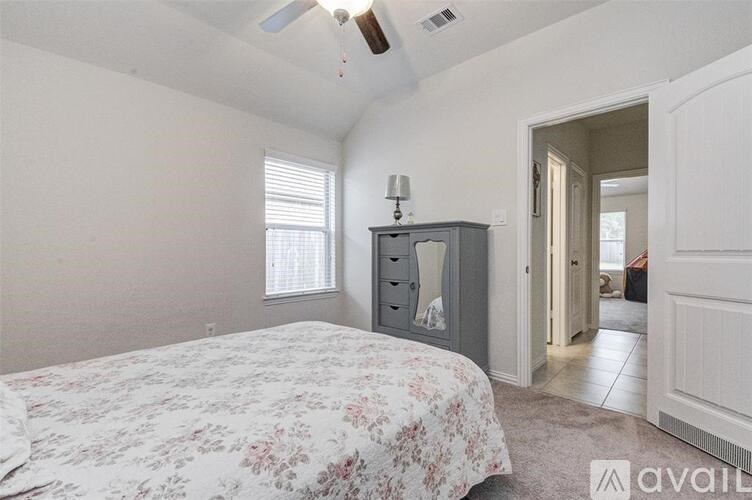 A bedroom with a floral bedspread and a grey chest of drawers.