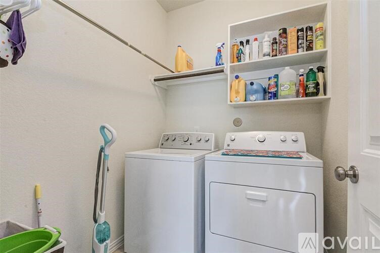 A laundry room with a washer and dryer, a mop, and cleaning supplies.