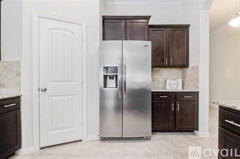 A stainless steel refrigerator in a kitchen with brown cabinets.