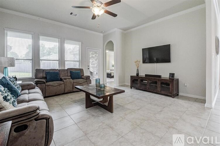 A living room with a brown sofa, a wooden coffee table, and a flat screen TV mounted on the wall.