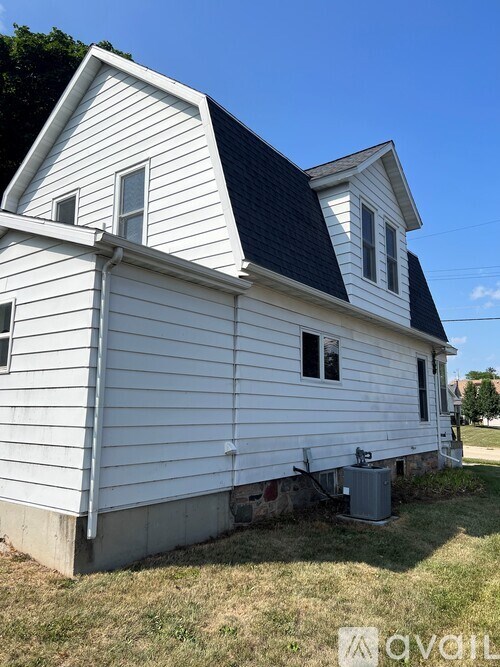 A white house with a black roof and a window with a screen door.