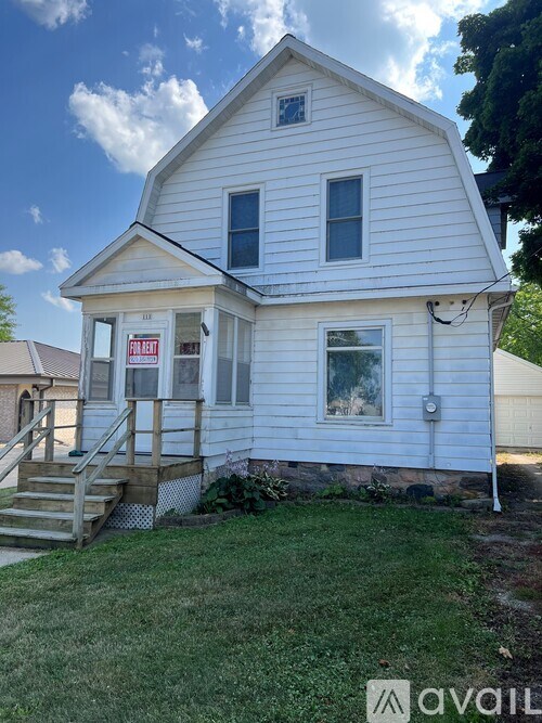 A white house with a "For Rent" sign in front.