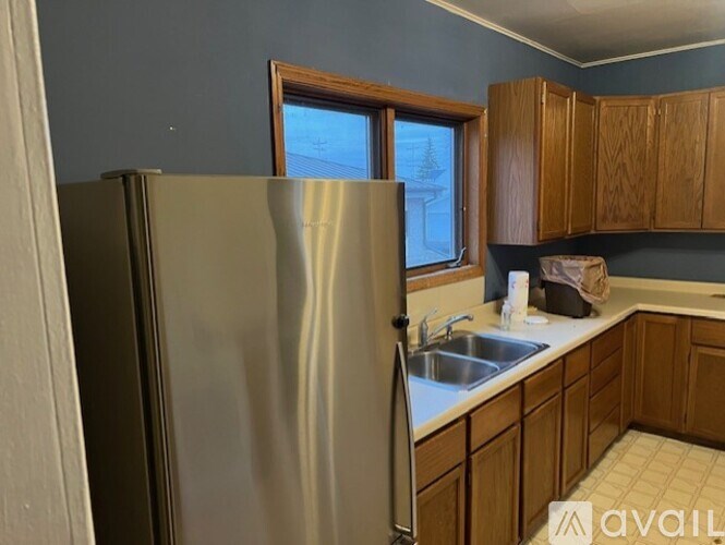 A kitchen with a stainless steel refrigerator and wooden cabinets.