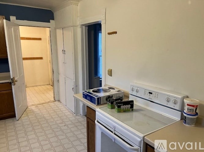A kitchen with a white stove top oven and white tiled floor.