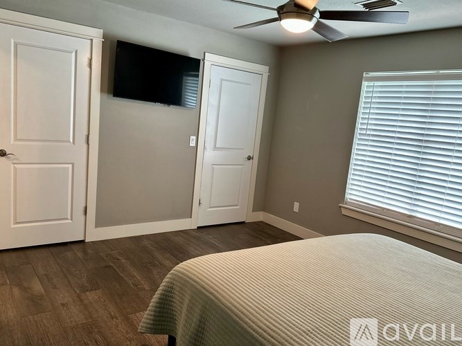 A room with a bed, a ceiling fan, and a window with blinds.