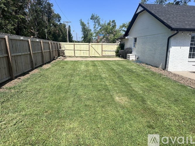 A backyard with a wooden fence and a white house.