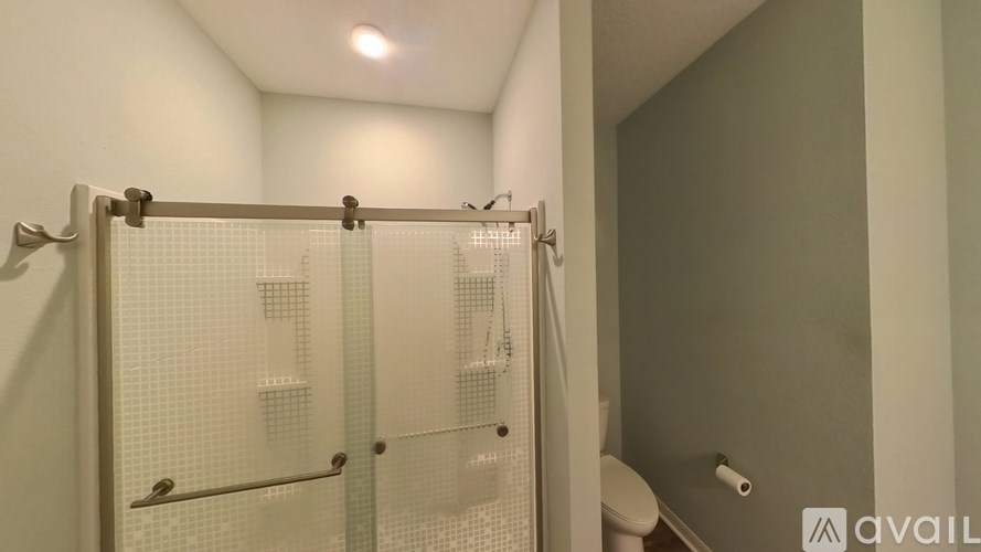 A bathroom with a glass shower door and a toilet.