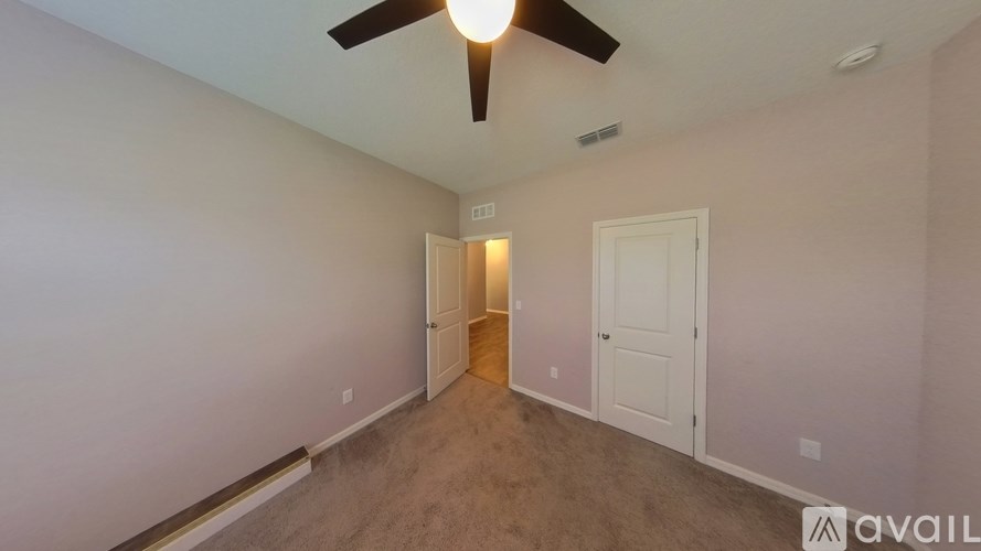 A room with a ceiling fan and two doors.