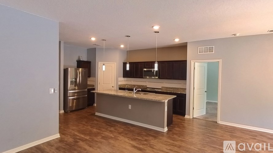 A modern kitchen with wooden floors and stainless steel appliances.