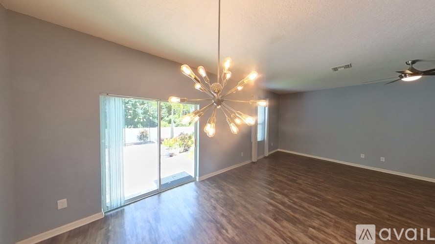 A room with a chandelier and sliding glass doors.
