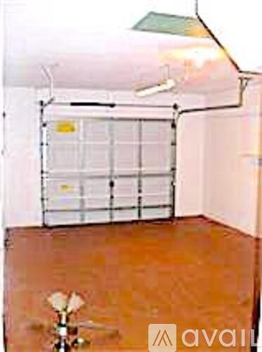 A room with a brown floor and a white wall with a window covered by a white curtain.