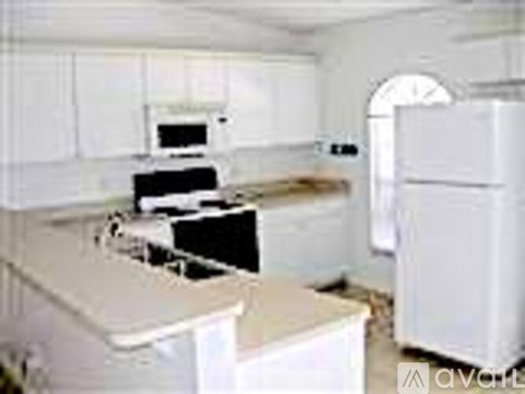 A white kitchen with a refrigerator, sink, and oven.