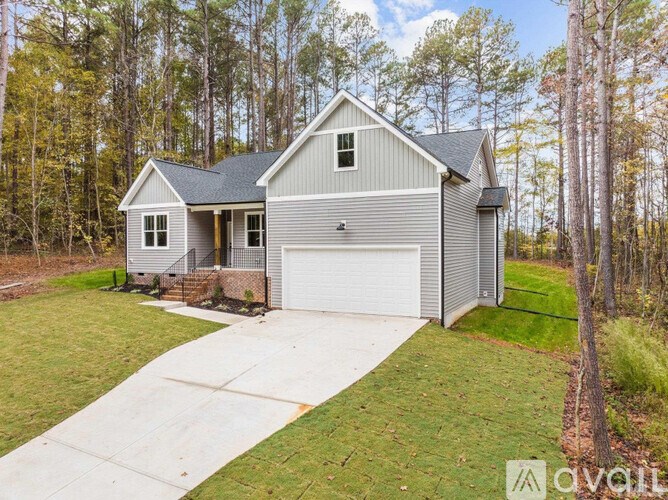 A house with a garage is surrounded by trees.