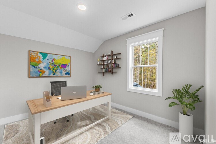 A room with a desk, laptop, and a painting on the wall.