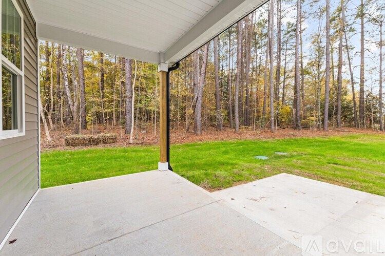 A patio with a white wall and a concrete floor.