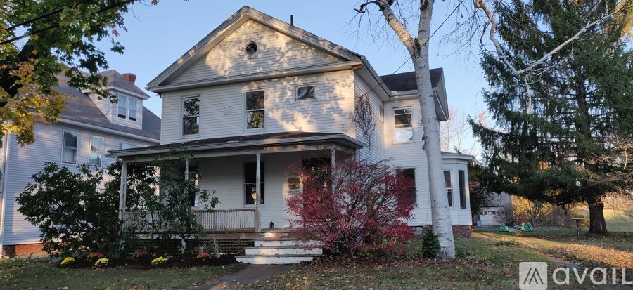 A house with a porch and a tree in front of it.