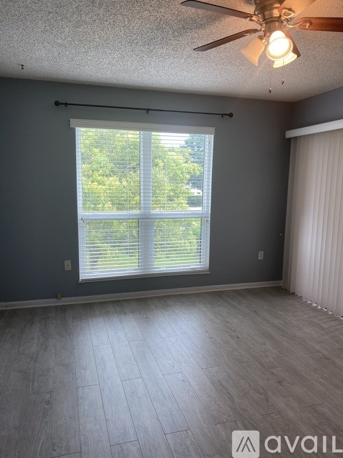 A room with a ceiling fan and a window with blinds.