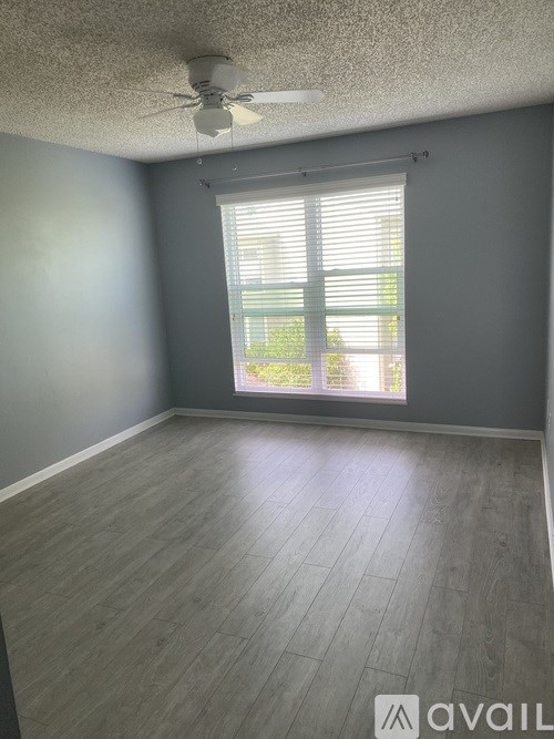 A room with a ceiling fan and a window with blinds.
