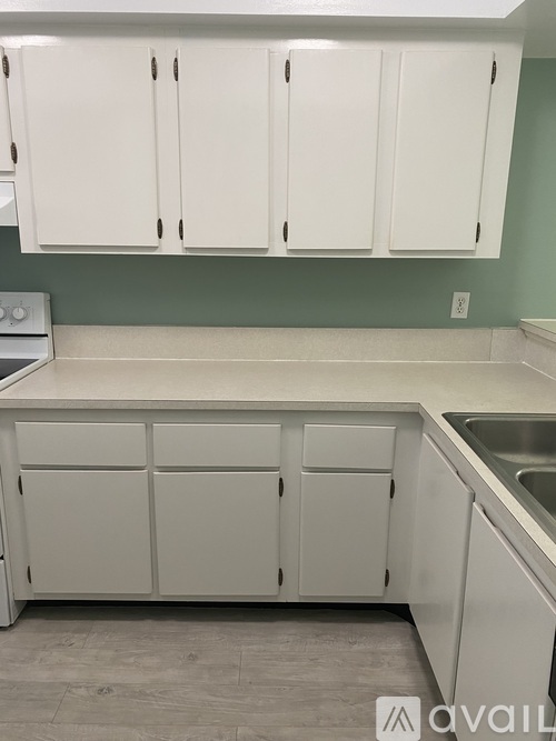 A kitchen with white cabinets and a green wall.