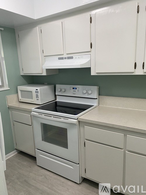 A kitchen with white appliances and cabinets.
