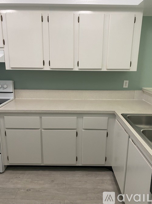 A kitchen with white cabinets and a green wall.