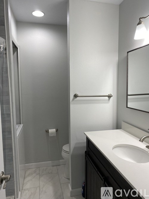 A bathroom with a toilet, sink, and mirror.