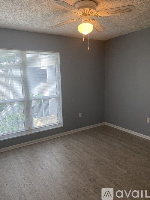 A room with a ceiling fan and a window with blinds.