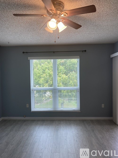 A room with a ceiling fan and a window with blinds.