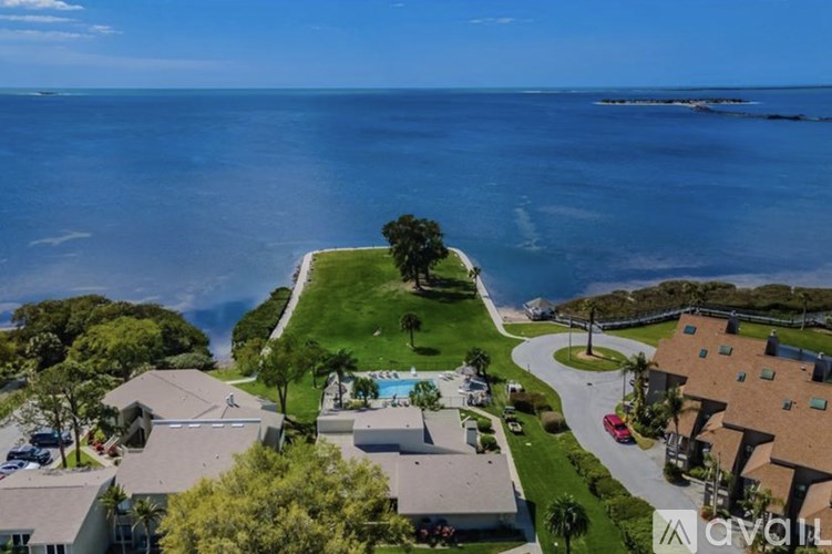 A bird's eye view of a residential area with houses, a swimming pool, and a beach in the background.