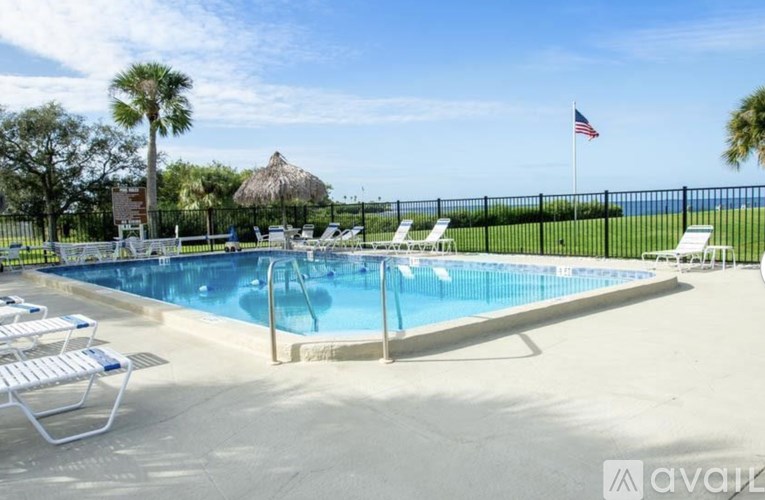 A pool surrounded by chairs and a fence with an American flag in the background.
