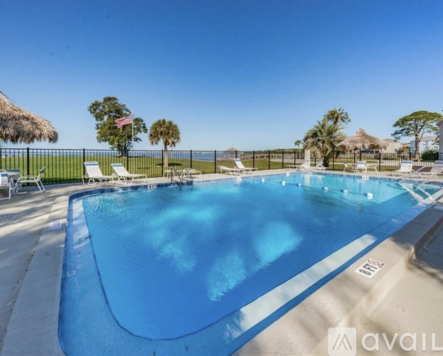 A large blue swimming pool surrounded by a fence and lounge chairs.