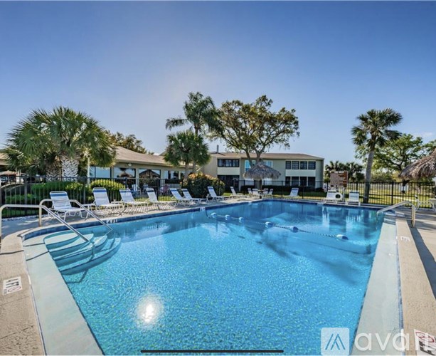 A large swimming pool with sun loungers and a building in the background.