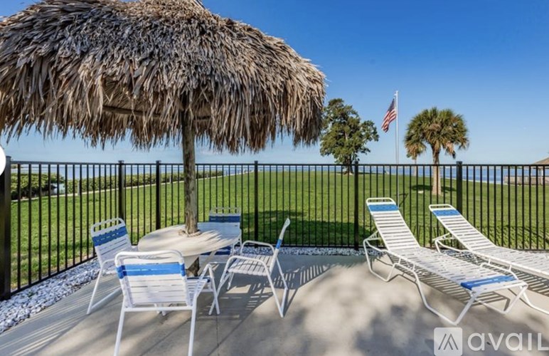 A patio with a thatched umbrella, chairs, and a table with a view of the ocean.