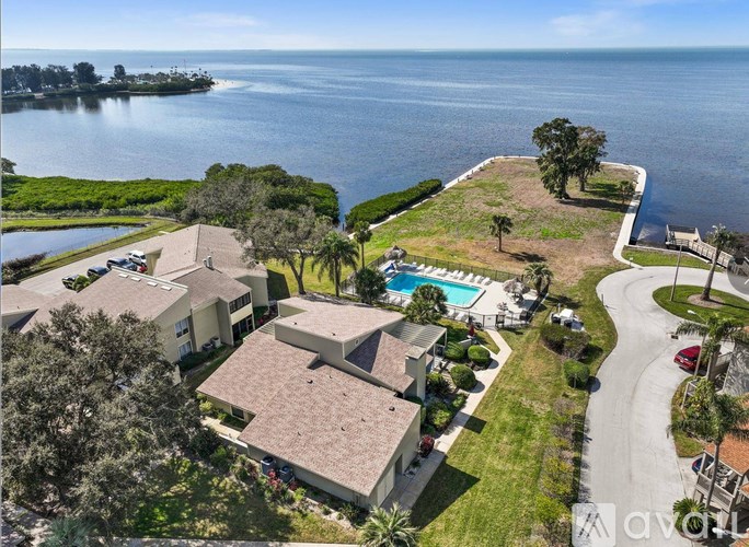 A bird's eye view of a residential area with houses, a swimming pool, and a body of water.