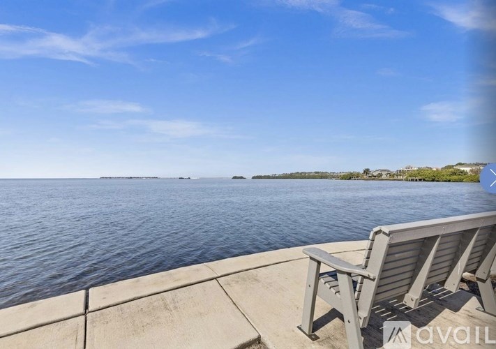A bench is on a concrete pier overlooking a body of water.