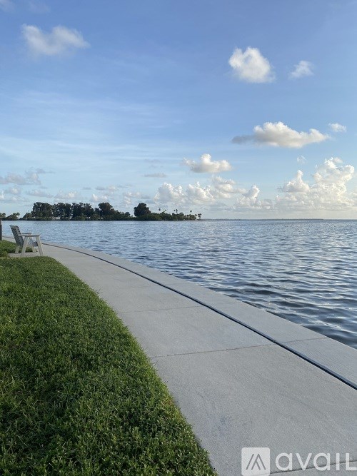 A bench sits on a concrete path next to a body of water.