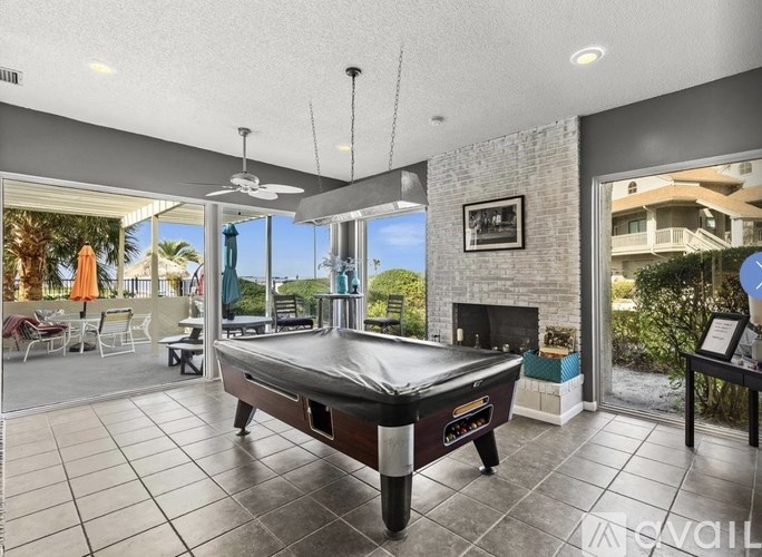 A pool table is in the middle of a room with a view of the outside.