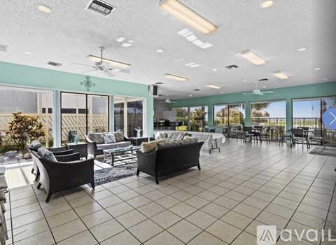 A spacious living room with a large couch and a ceiling fan.