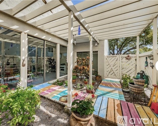 A patio with a white pergola and a table with a colorful tablecloth.