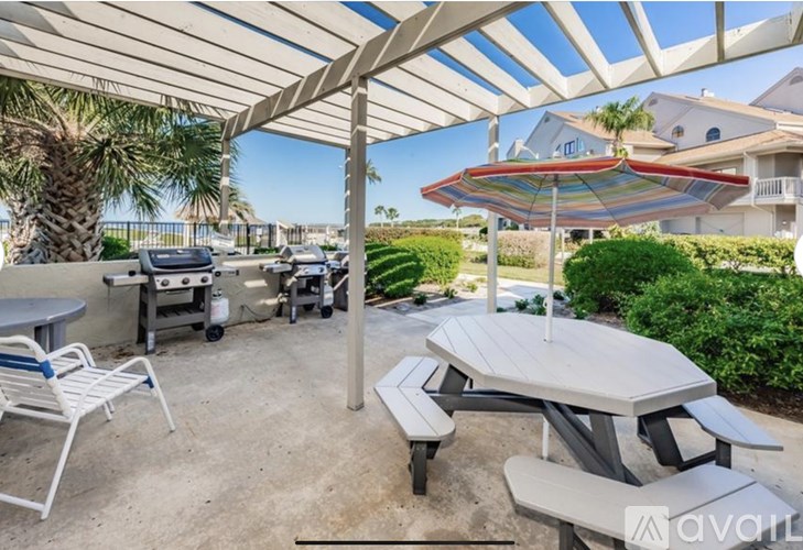 A patio with a table and chairs under a striped umbrella.