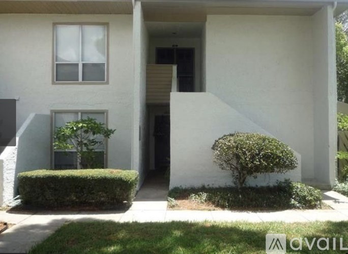 A white house with a green bush in front.