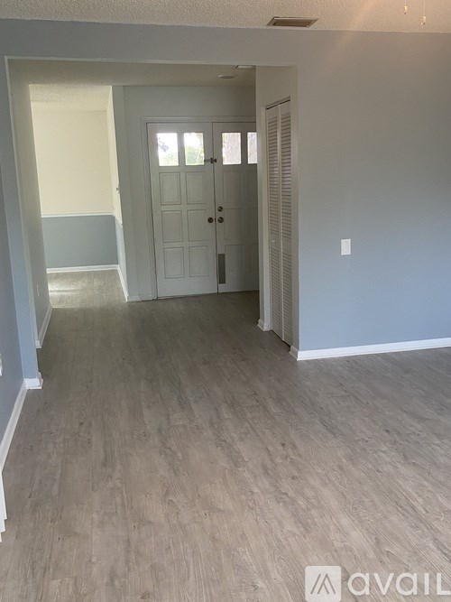 A room with a white door and wooden flooring.