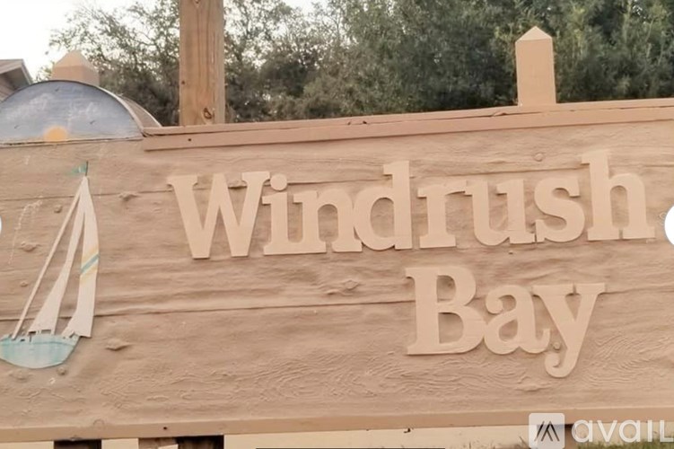 A wooden sign that says Windrush Bay with a sailboat on it.