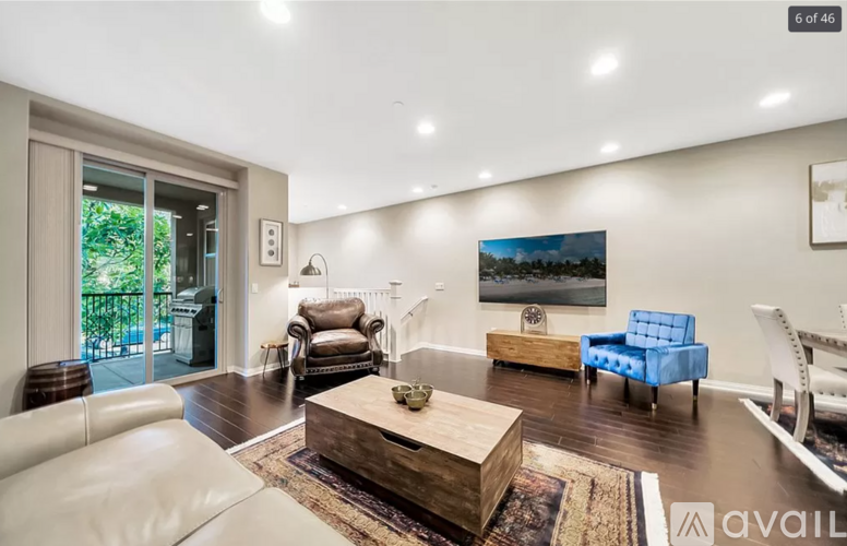 A living room with a white couch, a blue chair, and a painting on the wall.