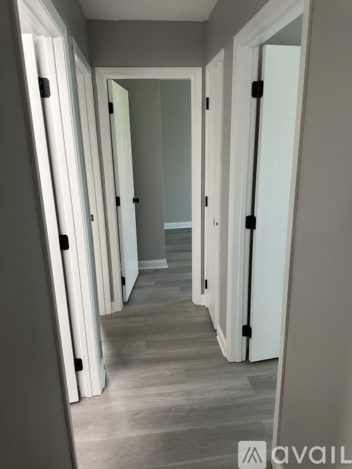 A hallway with white doors and a wooden floor.