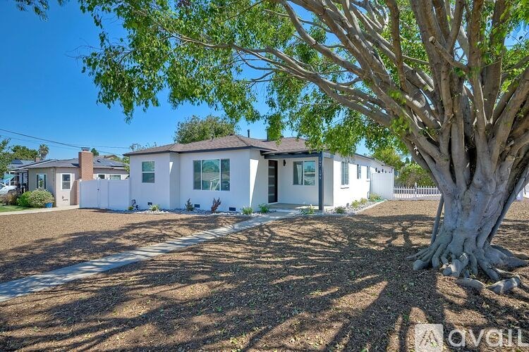 A white house with a tree in front of it.