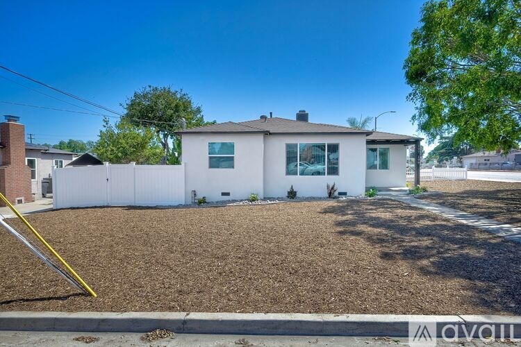 A house with a white fence and a gravel driveway is for sale.